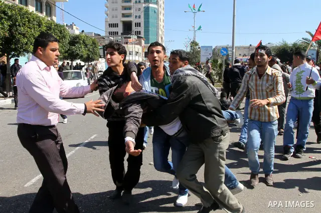 Palestinian demonstrators carry a wounded youth during brief clashes between Hamas supporters and protestors supporting other Palestinian factions, during a rally calling for Palestinian political unity between Gaza's Ha...
