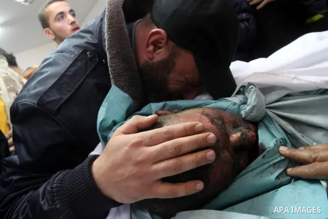 Palestinians stand next to the body of a Hamas militant killed in an Israeli air strike on a Hamas training camp, after they were brought to the morgue of Shifa hospital in Gaza City, Wednesday, March 16, 2011. Israeli f...