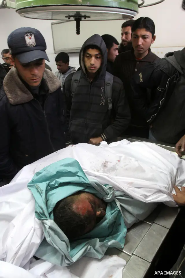 Palestinians stand next to the body of a Hamas militant killed in an Israeli air strike on a Hamas training camp, after they were brought to the morgue of Shifa hospital in Gaza City, Wednesday, March 16, 2011. Israeli f...