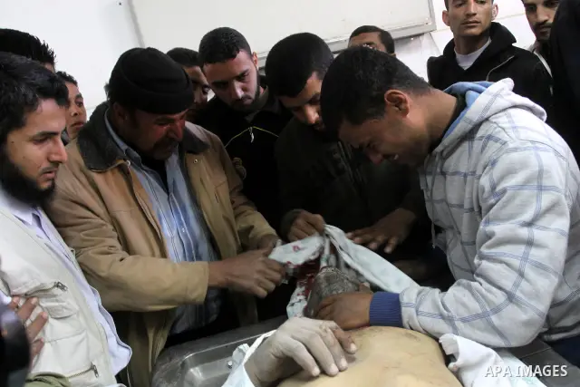 Palestinians stand next to the body of a Hamas militant killed in an Israeli air strike on a Hamas training camp, after they were brought to the morgue of Shifa hospital in Gaza City, Wednesday, March 16, 2011. Israeli f...