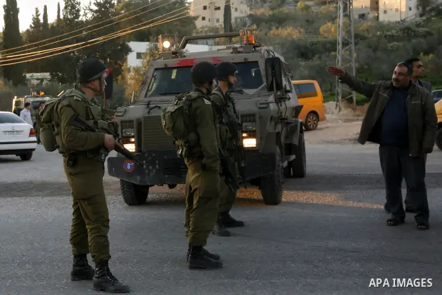 Israeli soldiers stand guard near the Israeli settlement of Qadumim between Qalqilya and Nablus in the West Bank after settlers torched the cars of two Palestinians working inside the settlement on March 17, 201. Photo b...
