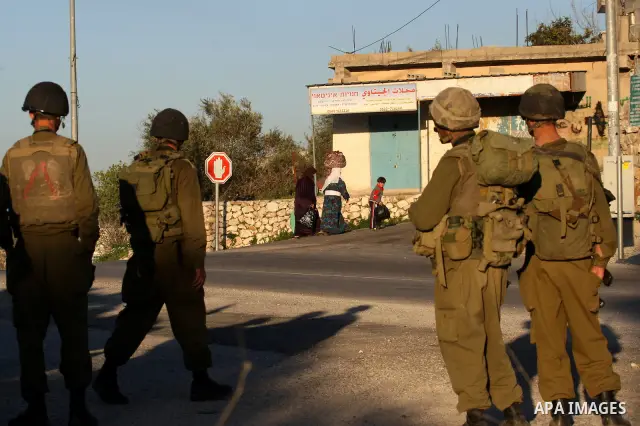 Israeli soldiers stand guard near the Israeli settlement of Qadumim between Qalqilya and Nablus in the West Bank after settlers torched the cars of two Palestinians working inside the settlement on March 17, 201. Photo b...