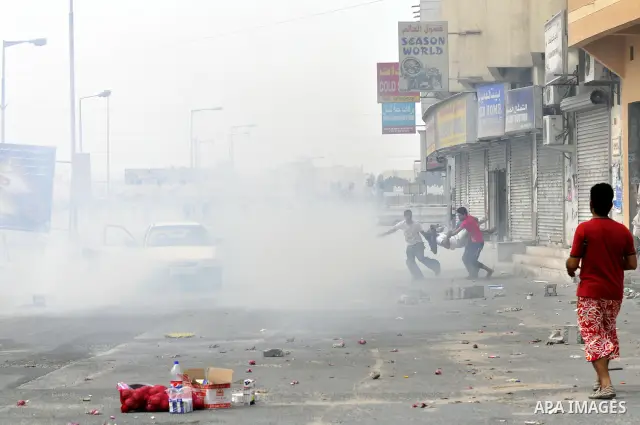 Anti-government protesters run from riot police, Thursday, March 17, 2011, as a tear gas canister explodes nearby in the Shiite Muslim village of Jidhafs, Bahrain, on the outskirts of the capital of Manama. Security forc...