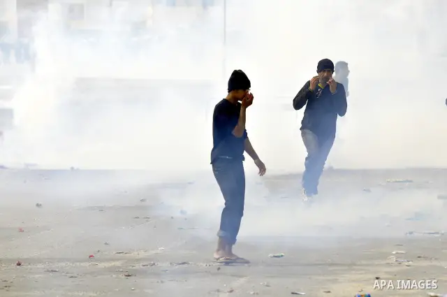 Anti-government protesters run from riot police, Thursday, March 17, 2011, as a tear gas canister explodes nearby in the Shiite Muslim village of Jidhafs, Bahrain, on the outskirts of the capital of Manama. Security forc...