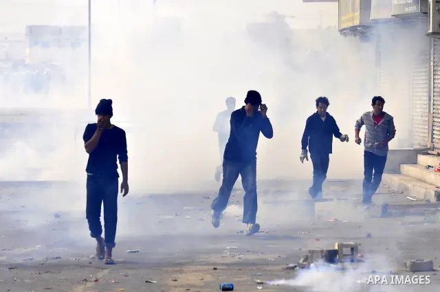 Anti-government protesters run from riot police, Thursday, March 17, 2011, as a tear gas canister explodes nearby in the Shiite Muslim village of Jidhafs, Bahrain, on the outskirts of the capital of Manama. Security forc...