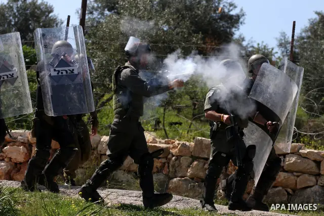 An Israeli soldier fires tear gas canister towards Palestinian youths during clashes following a weekly demonstration against Israel's separation barrier in the West Bank village of Bilin on March 18, 2011. Photo by Issa...