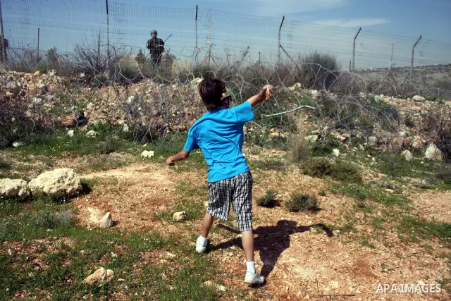 Palestinian youths throw stones at Israeli forces during clashes following a weekly demonstration against Israel's separation barrier in the West Bank village of Bilin on March 18, 2011. Photo by Issam Rimawi