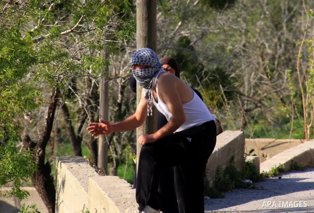A Palestinian youth hurls stons during clashes with Israeli settlers in the West Bank village of Yasuf south of Nablus, Friday, March 18, 2011. Photo by Wagdi Eshtayah