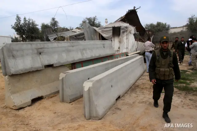A Hamas border policeman inspects a destroyed Hamas compound after an Israeli strike in Gaza City . Gaza militants fired dozens of shells into Israel, reportedly wounding at least two people, while Palestinians said five...