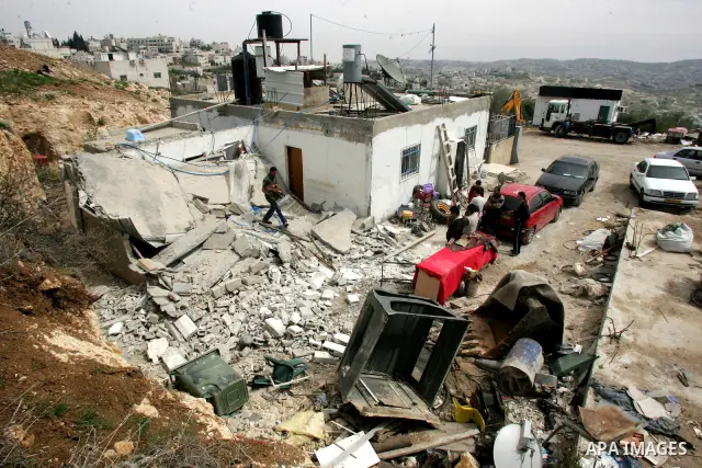 Palestinians stand on the rubble of their house after it was demolished by Israeli army in the Arab Jerusalem neighborhood of Sour Baher on March 19, 2011. Photo by Mahfouz Abu Turk
