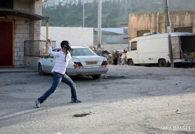 A Palestinian demonstrator throws stones at Israeli soldiers during clashes in the Shufat refugee camp in Jerusalem on March 19, 2011. Hundreds of Palestinians clashed with security forces in east Jerusalem on as tension...