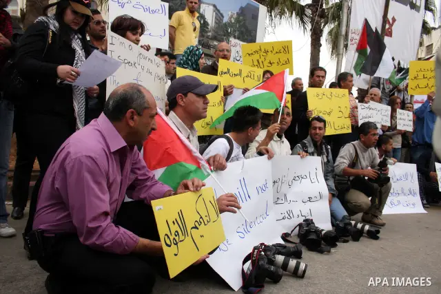 Journalists and photographers hold banners during a protest in the West Bank city of Ramallah, 20 March 2011 following the raid on Reuters office by security forces in Gaza city on 19 March. Photo by Issam Rimawi