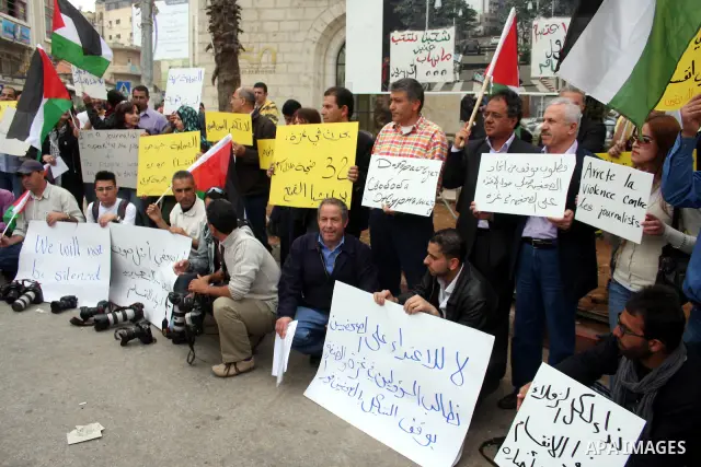 Journalists and photographers hold banners during a protest in the West Bank city of Ramallah, 20 March 2011 following the raid on Reuters office by security forces in Gaza city on 19 March. Photo by Issam Rimawi