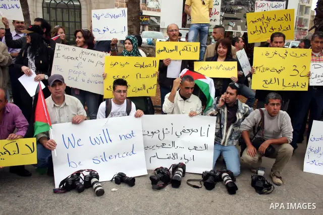 Journalists and photographers hold banners during a protest in the West Bank city of Ramallah, 20 March 2011 following the raid on Reuters office by security forces in Gaza city on 19 March. Photo by Issam Rimawi