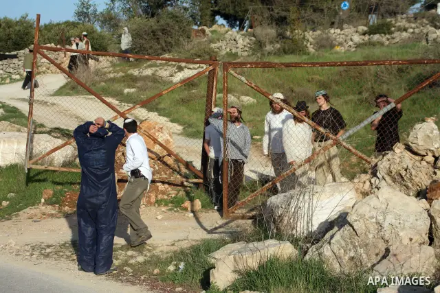 Israeli settlers from the Kharsina settlement throw stones at Palestinian cars on March 21,2011 near Hebron in the Israeli-occupied West Bank, as three Palestinians were wounded by Israeli settlers near the West Bank tow...