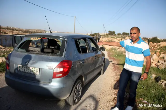 A Palestinian man gestures near his damaged car after Jewish settlers from the Kharsina settlement threw stones at Palestinian drivers on March 21,2011 near Hebron in the Israeli-occupied West Bank, as three Palestinians...
