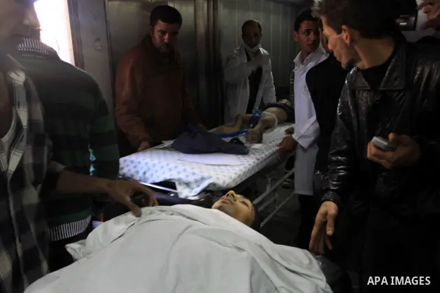 Palestinians stand next to the body of a Palestinian killed in an Israeli shells, after was brought to the morgue of Shifa hospital in Gaza City, Tuesday, March 22, 2011. Israeli tank fire struck a house in the Gaza Stri...