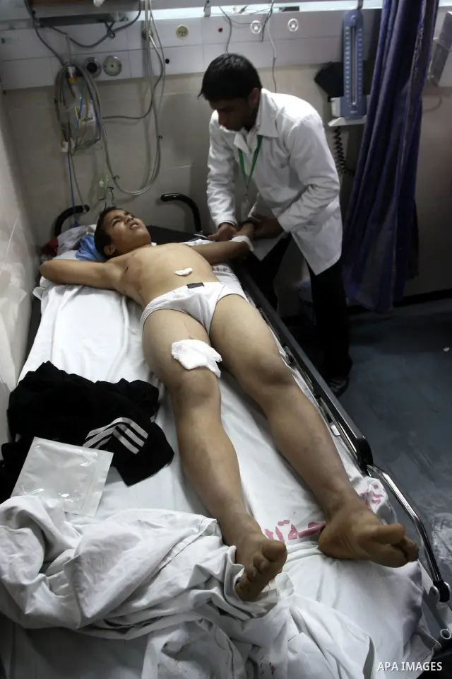 Palestinian medics stand next to a Palestinian injured in an Israeli shells, after was brought to the Shifa hospital in Gaza City, Tuesday, March 22, 2011. Israeli tank fire struck a house in the Gaza Strip on Tuesday, k...