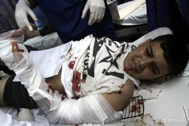 Palestinian medics stand next to a Palestinian injured in an Israeli shells, after was brought to the Shifa hospital in Gaza City, Tuesday, March 22, 2011. Israeli tank fire struck a house in the Gaza Strip on Tuesday, k...