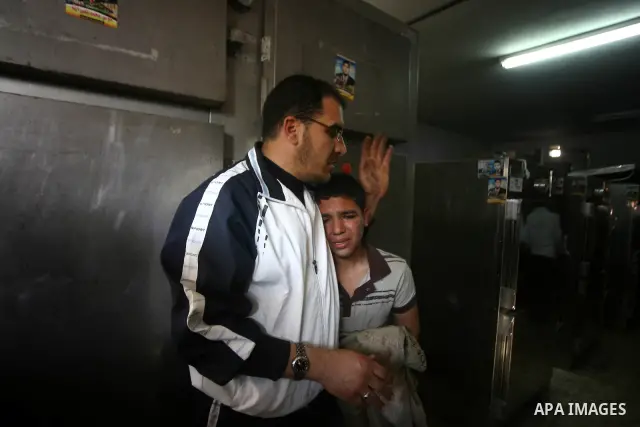 A Palestinian youth mourn next to the body of a Palestinian killed in an Israeli shells, after was brought to the morgue of Shifa hospital in Gaza City, Tuesday, March 22, 2011. Israeli tank fire struck a house in the Ga...