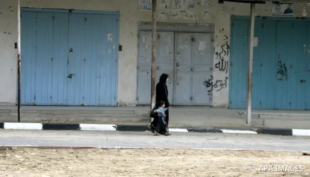 Palestinians walk in front of closed shops at Rafah, southern Gaza Strip, as the Palestinian government in Gaza announced Wednesday, a day of mourning for the lives of eight martyrs killed yesterday in the Israeli raids...