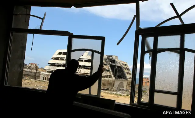 A Palestinian adjusts his broken windows in front of destroyed security office in Gaza City, on March 25, 2011, as Israeli aircraft attacked four targets in the Gaza Strip during the night, lightly wounding three people,...