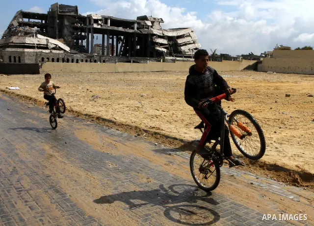 Palestinian boys ride past destroyed security office in Gaza City, on March 25, 2011, as Israeli aircraft attacked four targets in the Gaza Strip during the night, lightly wounding three people, in response to Palestinia...