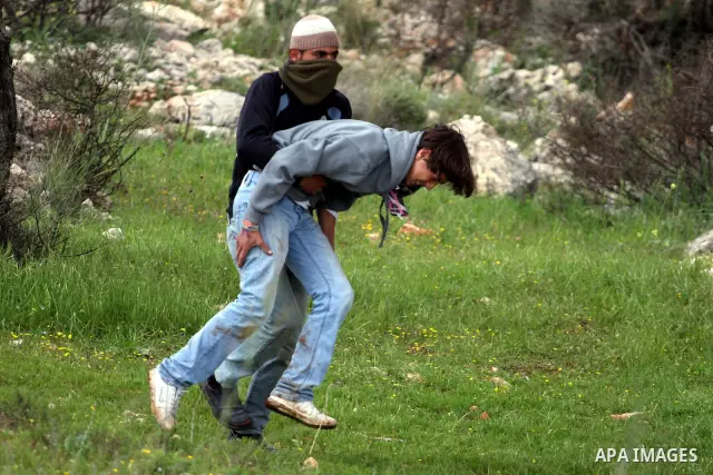 Palestinian protesters help a wounded youth during clashes following a weekly demonstration against Israel's separation barrier in the West Bank village of Bilin on March 25, 2011. Photo by Issam Rimawi