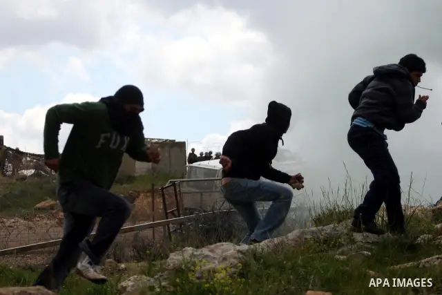 Palestinian youths throw stones at Israeli forces during clashes following a weekly demonstration against Israel's separation barrier in the West Bank village of Bilin on March 25, 2011. Photo by Issam Rimawi