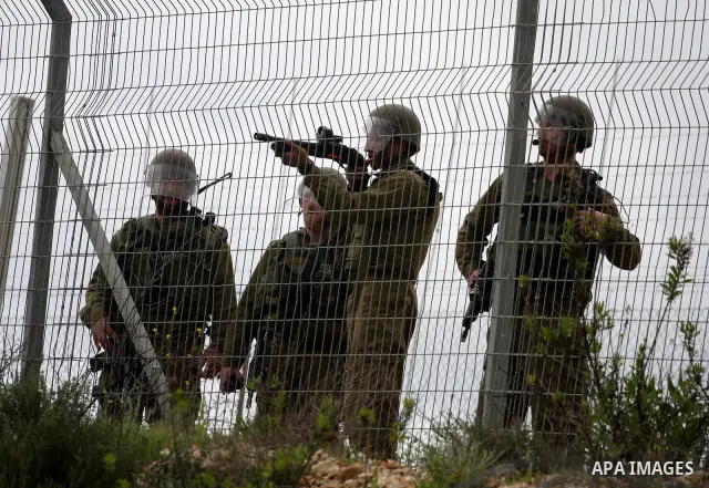 An Israeli soldier fires tear gas canisters towards Palestinian youths during clashes following a weekly demonstration against Israel's separation barrier in the West Bank village of Bilin on March 25, 2011. Photo by Iss...