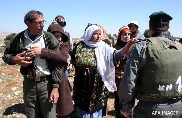 A Palestinian woman quarrels with Israeli soldiers during a protest against Jewish settlers in the West Bank village of Yatta, south of the West Bank city of Hebron, on 26 March 2011.Photo by Najeh Hahlamoun