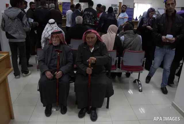 Palestinians receive the financial assistance from the Ministry of Social Affairs at a bank in the West Bank city of Salfit on March 26, 2011. Photo by Issam Rimawi