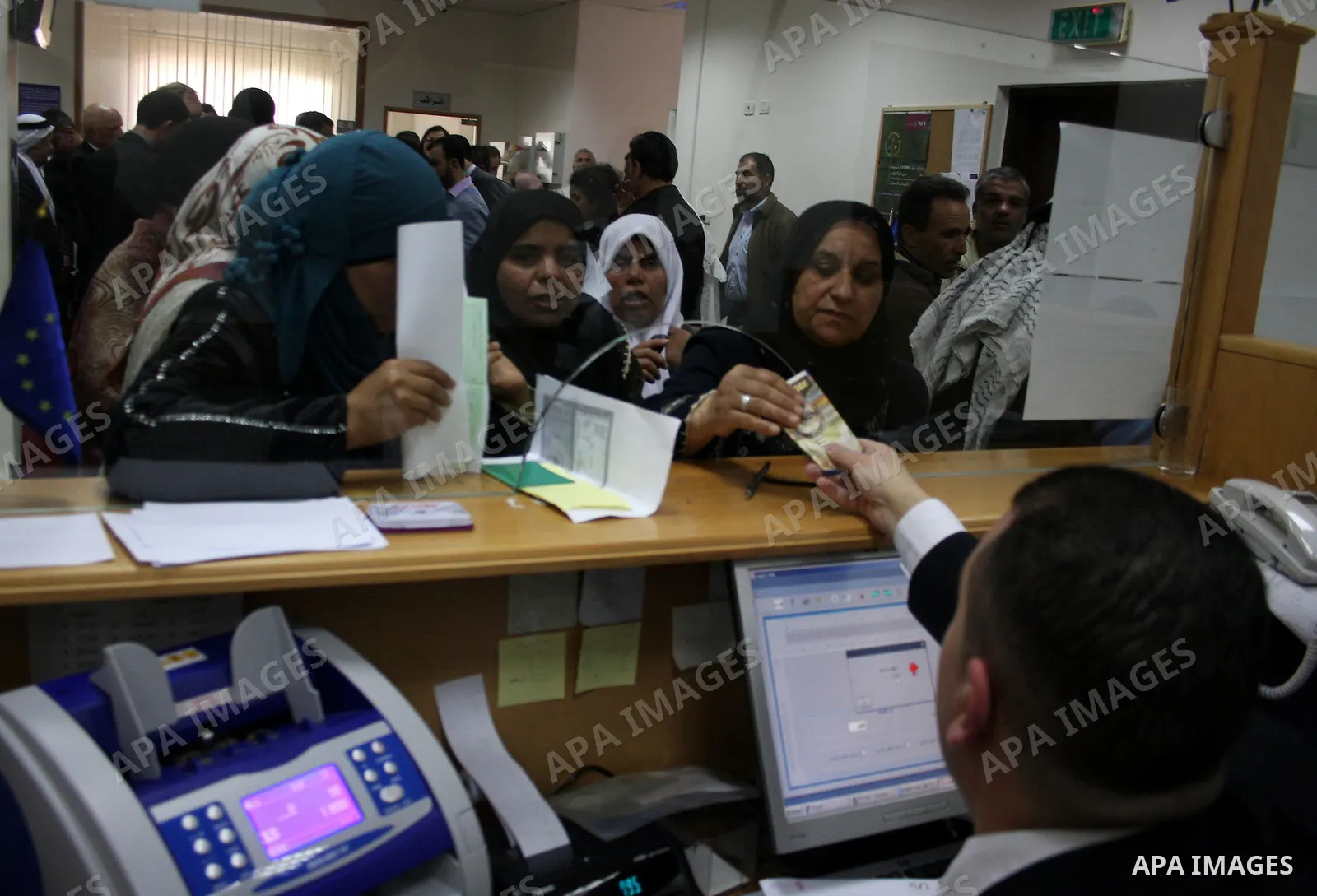 Palestinians receive the financial assistance from the Ministry of Social Affairs at a bank in the West Bank city of Salfit on March 26, 2011. Photo by Issam Rimawi