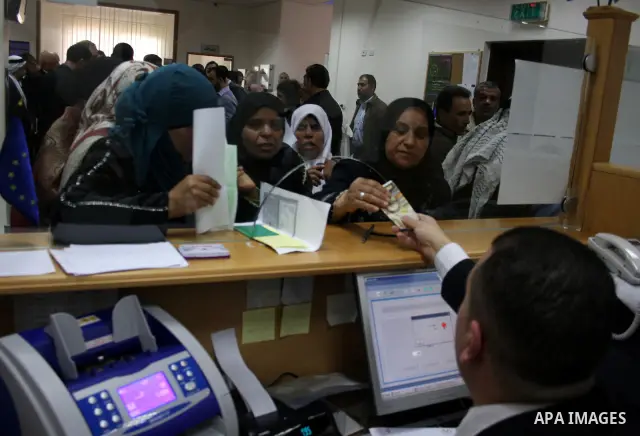 Palestinians receive the financial assistance from the Ministry of Social Affairs at a bank in the West Bank city of Salfit on March 26, 2011. Photo by Issam Rimawi
