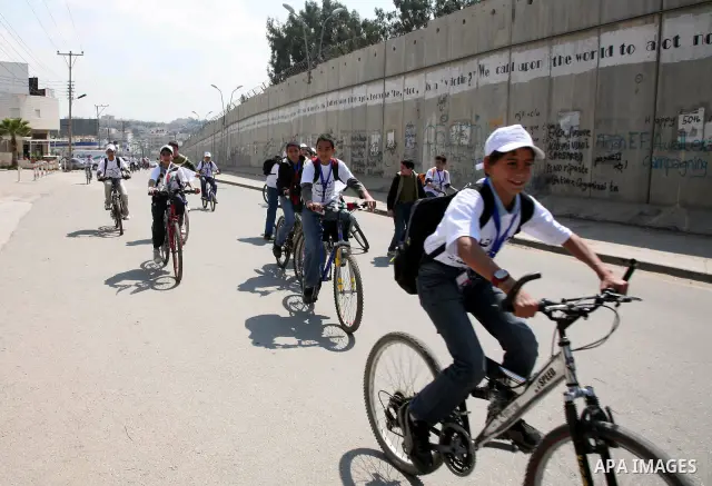 Palestinian children ride their bikes near the Israeli separation barrier during a festival under the title 'yes to life, yes to sports, no drug', in Al-Ram in the West Bank with the participation of the Directorate of E...