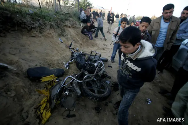 Palestinian boys stand next to the destroyed motorcycle that was ridden by Abu Mohammed Muammar and a fellow member of the Al-Quds Brigade, Islamic Jihad's armed wing, when they were hit by an Israeli warplanes strike in...