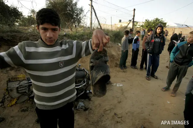 Palestinian boys stand next to the destroyed motorcycle that was ridden by Abu Mohammed Muammar and a fellow member of the Al-Quds Brigade, Islamic Jihad's armed wing, when they were hit by an Israeli warplanes strike in...