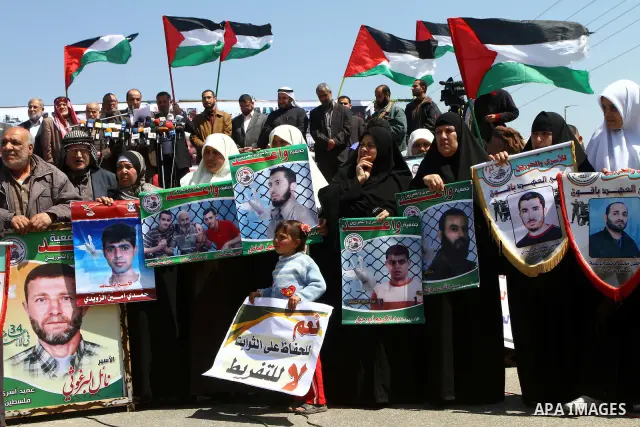 Palestinians wave their national flag and hold pictures of Palestinian prisoners jailed in Israel during a sit-in in Beit Hanun, northern Gaza Strip, on March 30, 2011 as hundreds of people across Israel and Palestinian...