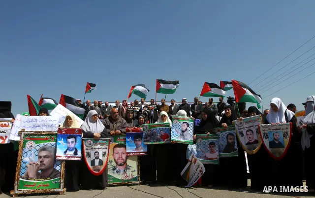 Palestinians wave their national flag and hold pictures of Palestinian prisoners jailed in Israel during a sit-in in Beit Hanun, northern Gaza Strip, on March 30, 2011 as hundreds of people across Israel and Palestinian...