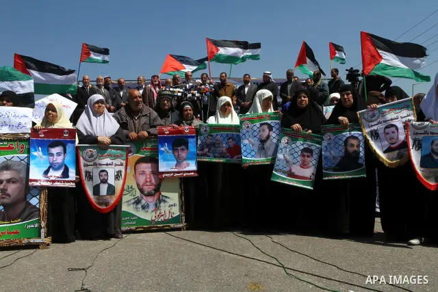 Palestinians wave their national flag and hold pictures of Palestinian prisoners jailed in Israel during a sit-in in Beit Hanun, northern Gaza Strip, on March 30, 2011 as hundreds of people across Israel and Palestinian...