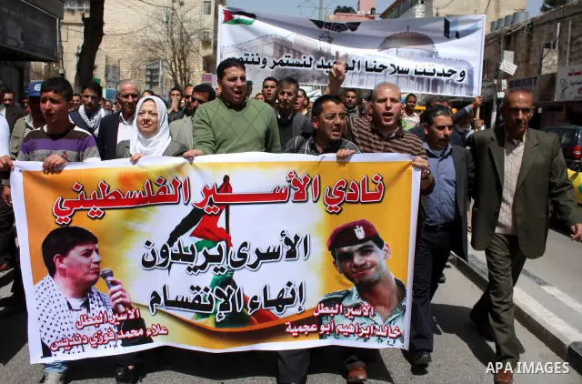 Palestinian protesters take part in a march in solidarity with Palestinian prisoners in Israeli jails and calling for end the split between the two rival leading Palestinian factions Fatah and Hamas, in the West Bank cit...