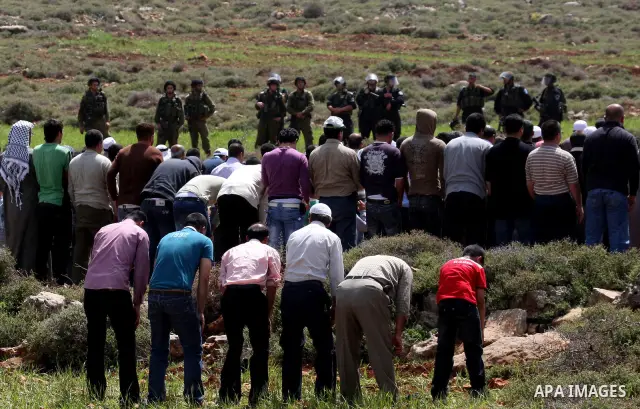 Israeli soldiers keep watch as Palestinians perform Friday prayers on an open field in the village of Qusra, near the Jewish settlement of Shilo, in the Israeli-occupied West Bank, on April 1, 2011. Photo by Wagdi Eshtay...