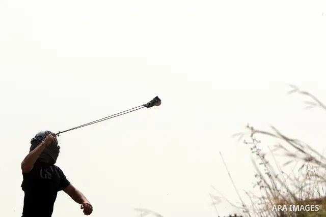 Palestinian demonstrators hurl stones towards Israeli forces during clashes following a weekly demonstration against Israel's separation barrier in the Palestinian West Bank village of Bilin on April 01, 2011. Photo by I...