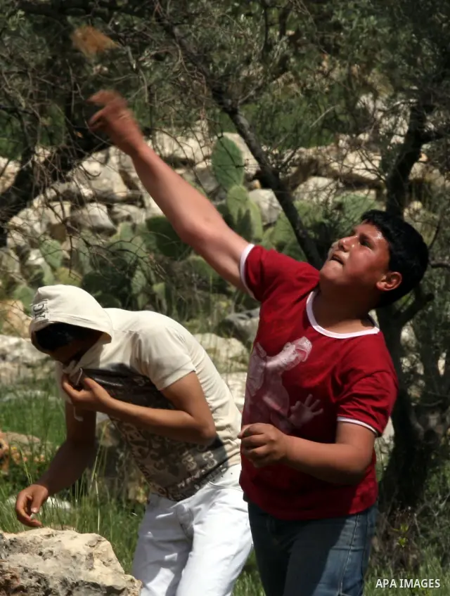 Palestinian demonstrators hurl stones towards Israeli forces during clashes following a weekly demonstration against Israel's separation barrier in the Palestinian West Bank village of Bilin on April 01, 2011. Photo by I...