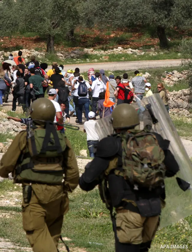 Israeli forces run behind demonstrators during clashes following a weekly demonstration against Israel's separation barrier in the Palestinian West Bank village of Bilin on April 01, 2011. Photo by Issam Rimawi