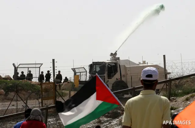 Palestinian protesters run a way as colored water is sprayed by the Israeli army from a water canon during the weekly demonstration against Israel's controversial separation barrier in the village of Bilin, near the West...