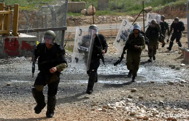 Israeli forces run behind demonstrators during clashes following a weekly demonstration against Israel's separation barrier in the Palestinian West Bank village of Bilin on April 01, 2011. Photo by Issam Rimawi