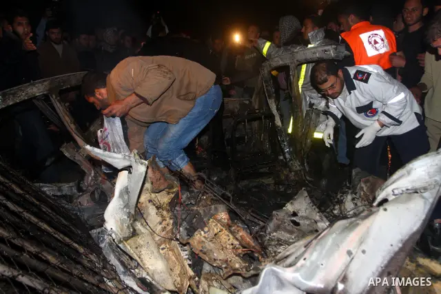 Members of Hamas' security forces inspect a car after an Israeli air strike in Deir Al-Balah in the central Gaza Strip early April 2, 2011. Israeli aircraft killed three Palestinian gunmen in the southern Gaza Strip earl...