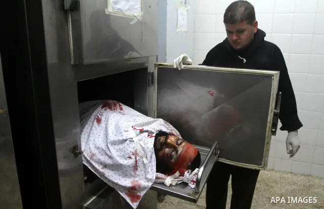 Members of Hamas' security forces stand next to the body of a militant after an Israeli air strike in Deir Al-Balah in the central Gaza Strip April 2, 2011. Israeli aircraft killed three Palestinian gunmen in the souther...