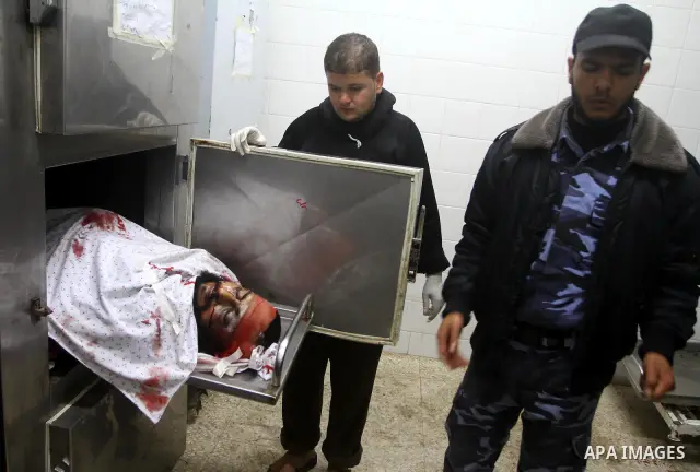 Members of Hamas' security forces stand next to the body of a militant after an Israeli air strike in Deir Al-Balah in the central Gaza Strip April 2, 2011. Israeli aircraft killed three Palestinian gunmen in the souther...